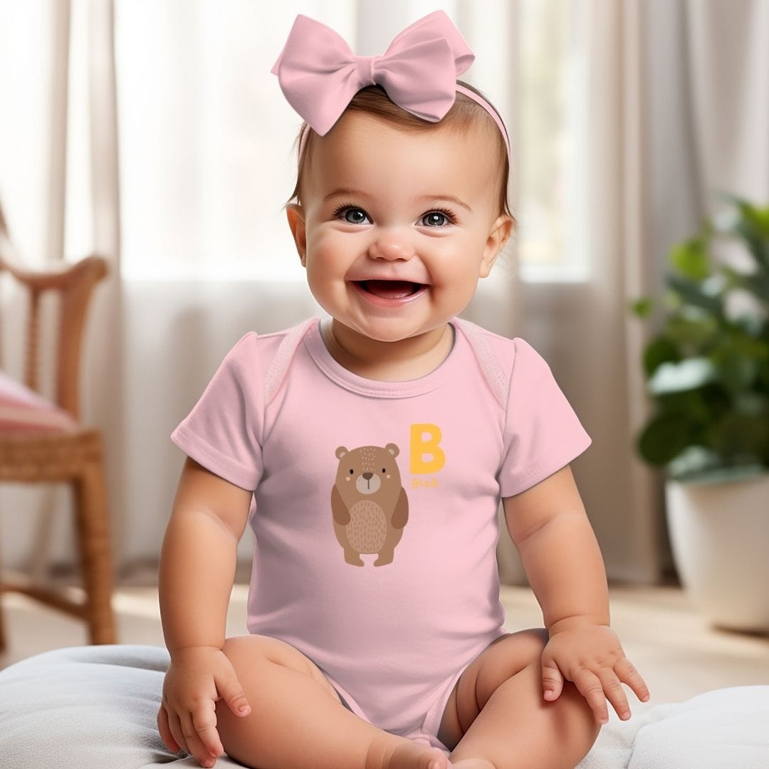 a baby girl sitting on a bed wearing a pink shirt with a bear on it